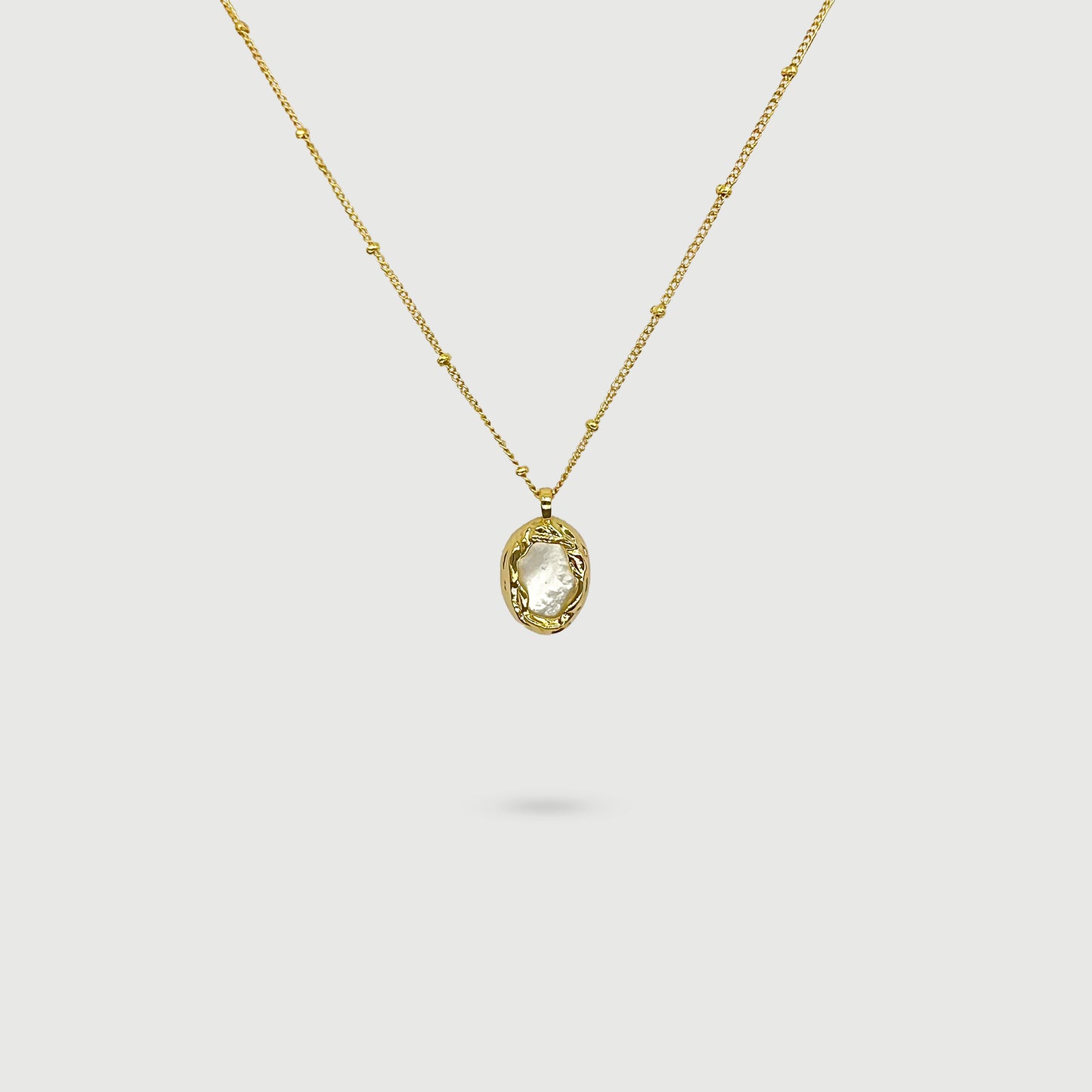 Collier coquille de perle ovale entourée de tissages dorés