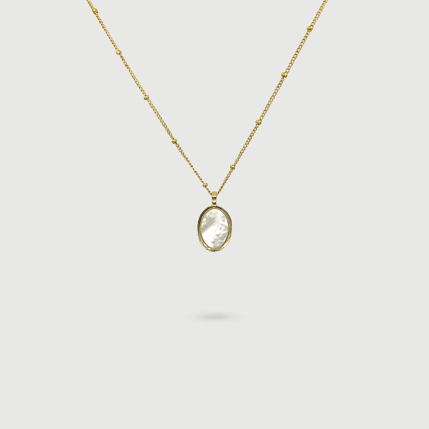 Collier coquille de perle ovale entourée de tissages dorés