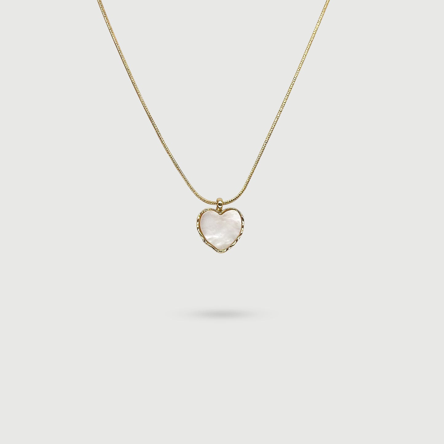 Collier coquille de perle en forme de cœur entourée de tissages dorés