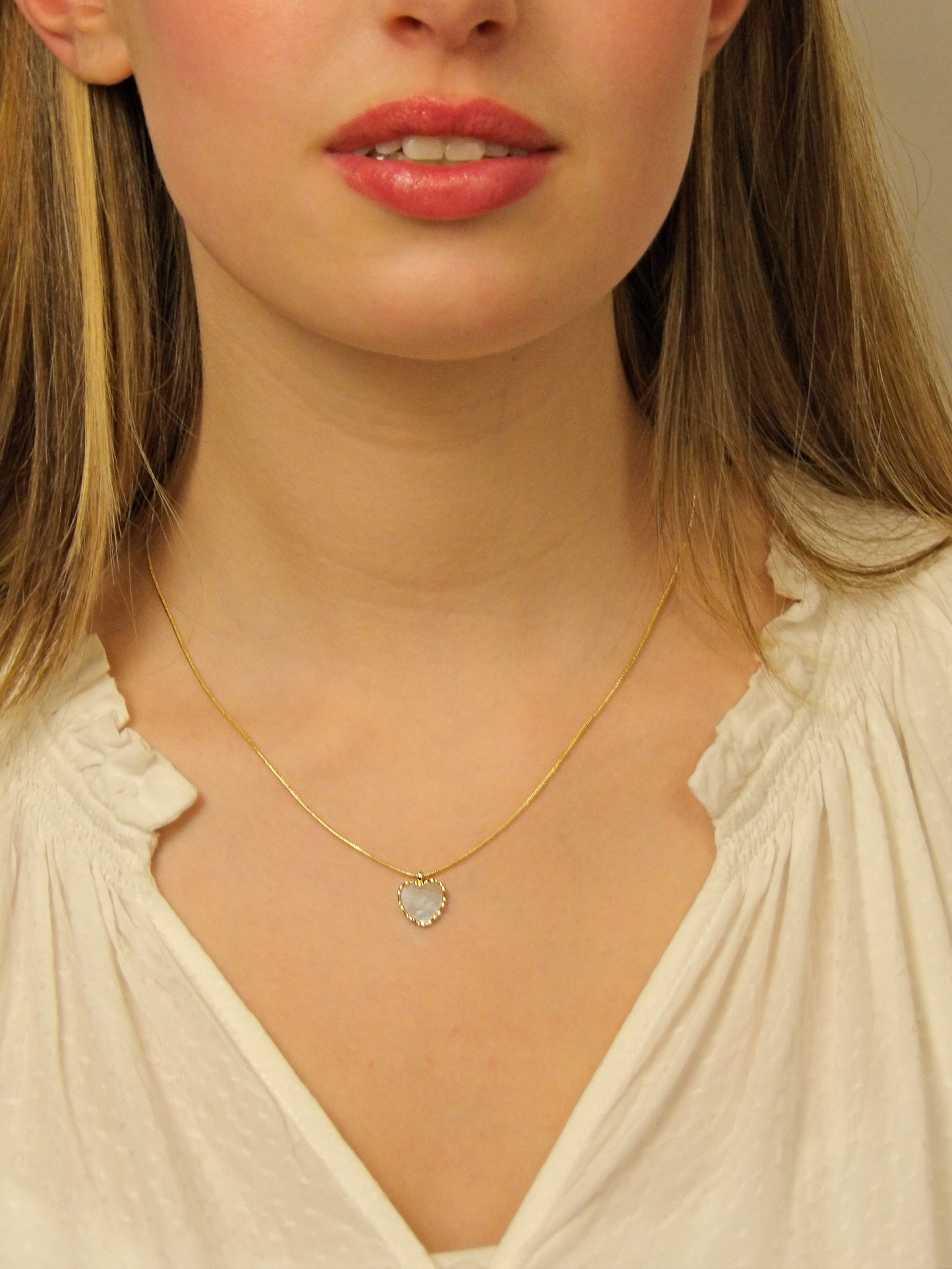 Collier coquille de perle en forme de cœur entourée de tissages dorés